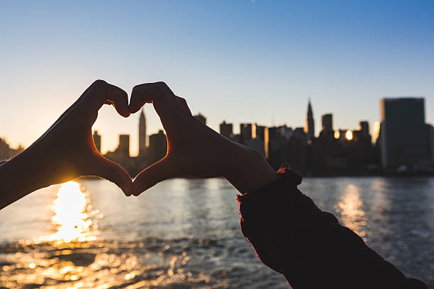 istock Heart Shaped Hands at Sunset, New York Skyline on Background 515809243