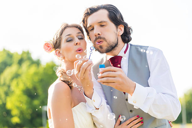 istock Wedding bride and groom blowing bubbles outside on field 515809838