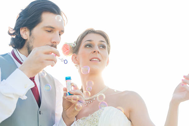Wedding couple blowing soap bubbles outside