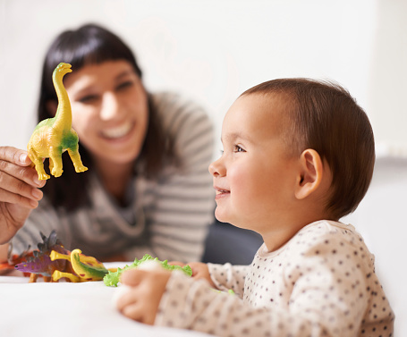 Shot of a happy mother playing with her daughter and toys