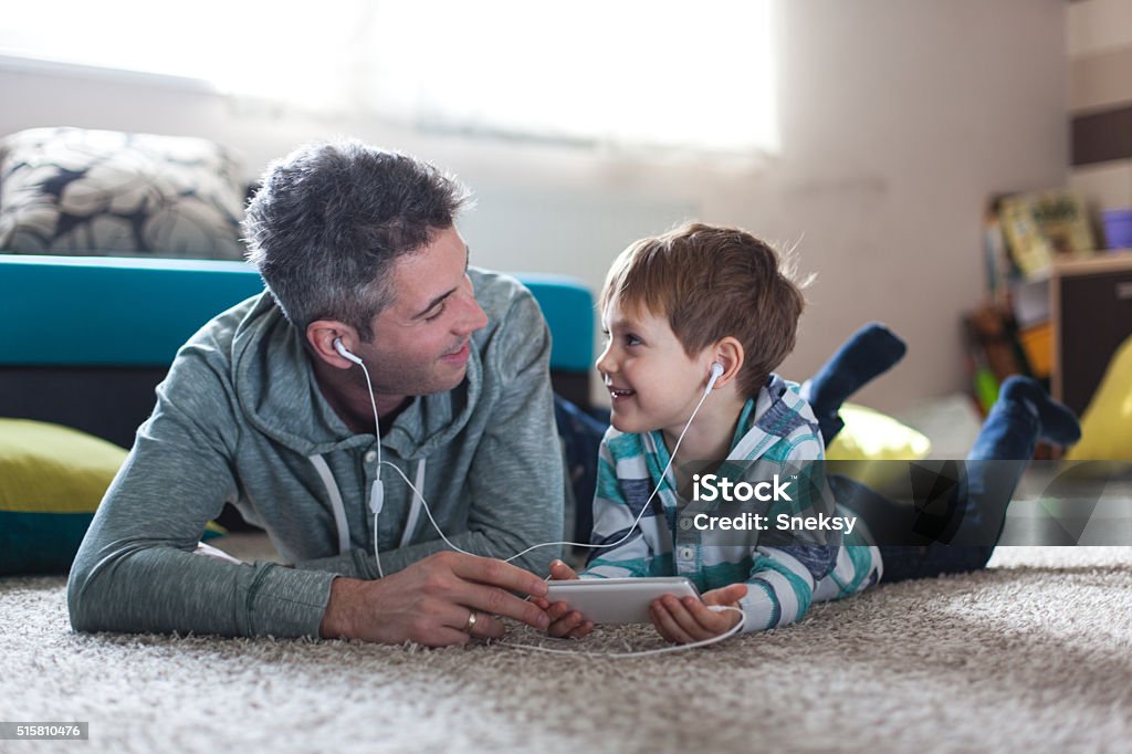Father and son listening music Smiling boy listenig music with his father Listening Stock Photo