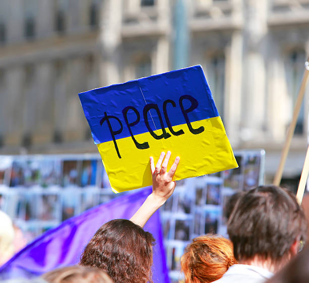 Peace sign on the ukrainian flag Paris, France - August 02, 2014 : Protest manifestation against war in Ukraine in Republic Square of Paris  peace demonstration stock pictures, royalty-free photos & images