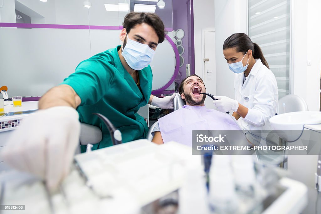 Dental process Dentist examining teeth of a patient with technician helping. Adult Stock Photo