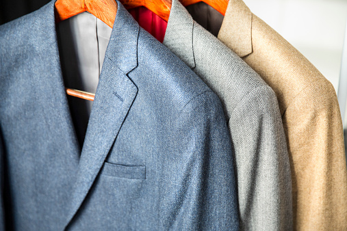 Cashmere suit jackets hanging from wooden hanger