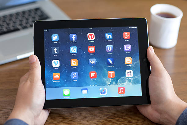 İstanbul, Turkey - January 16, 2016: Woman hands holding The New iPad displaying home screen on a desk. The iPad, produced by Apple Computer, Inc.