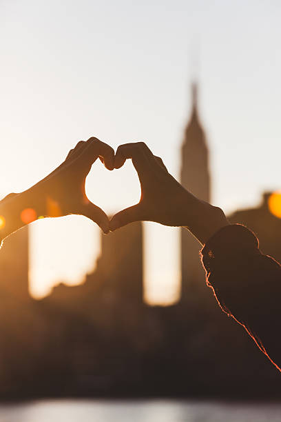 istock Heart Shaped Hands at Sunset, New York Skyline on Background 515836301