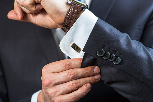 Elegant man correcting his cufflinks and sleeve.