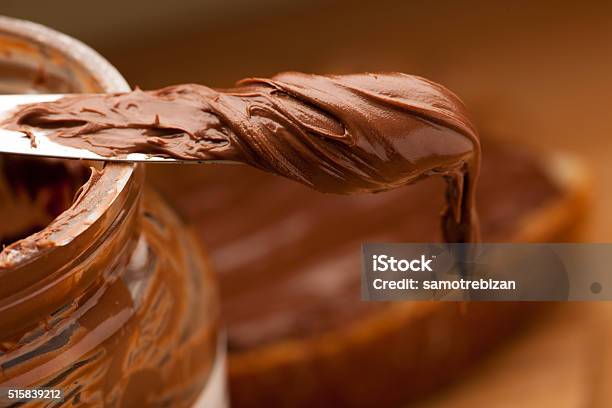 Knife Full Of Sweet Chocolate Nougat Spread On Glass Jar Stock Photo - Download Image Now