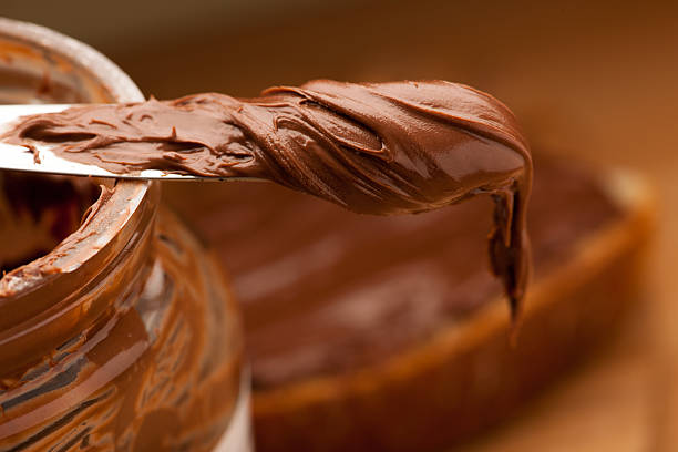 faca cheio de doces de chocolate em jarra de vidro nogado propagação. - chocolate spread imagens e fotografias de stock