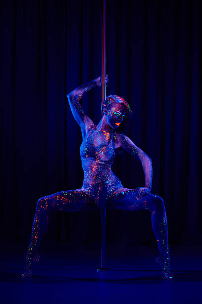 Female pole dancer in neon colours under ultraviolet (UV) light stock photo