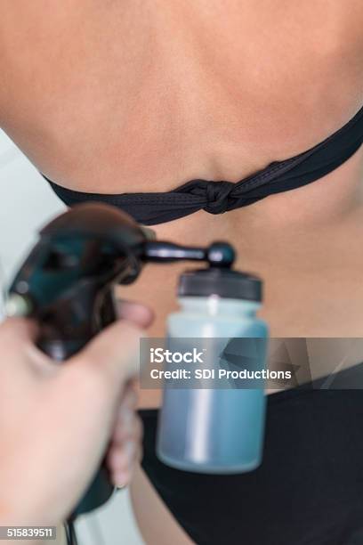 Tan Spray Being Applied To Womans Back In Tanning Booth Stock Photo - Download Image Now