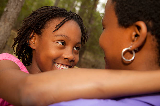 istock Relationships: African descent mother and daughter hug outside. 515842091