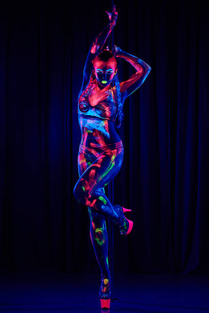 Female pole dancer in neon colours under ultraviolet (UV) light stock photo