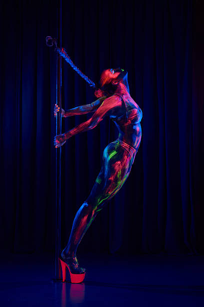 Female pole dancer in neon colours under ultraviolet (UV) light Female pole dancer in bright neon colours under ultraviolet (UV) light on background black pole dancers stock pictures, royalty-free photos & images