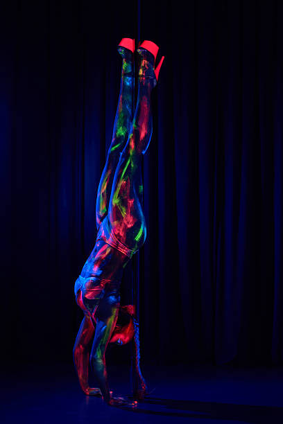 Female pole dancer in neon colours under ultraviolet (UV) light Female pole dancer in bright neon colours under ultraviolet (UV) light on background black pole dancers stock pictures, royalty-free photos & images