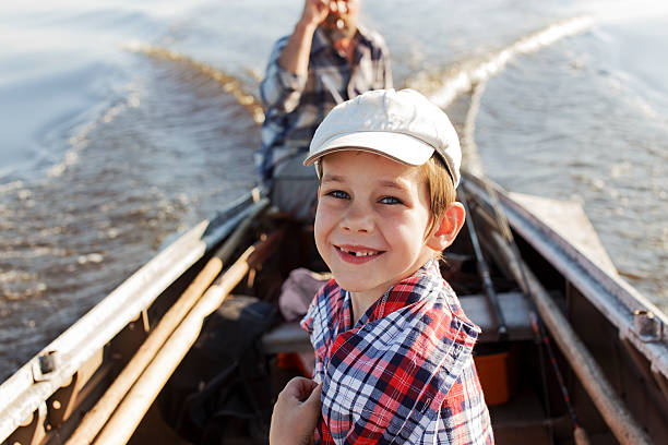 heureux petit garçon à cheval sur un bateau avec son grand-père - fishing lake grandfather grandson photos et images de collection