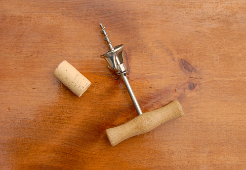 Corkscrew and cork on wood background