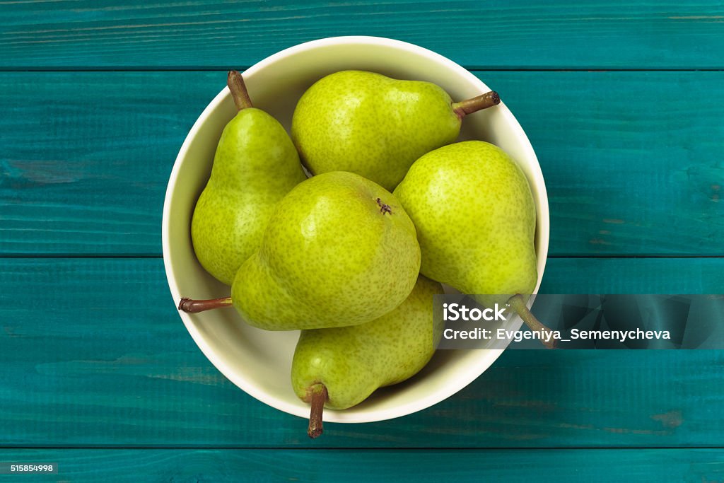 green pears in white bowl on blue wooden background. fresh juicy green pears in white bowl on blue wooden background, top view. rustic style. Pear Stock Photo