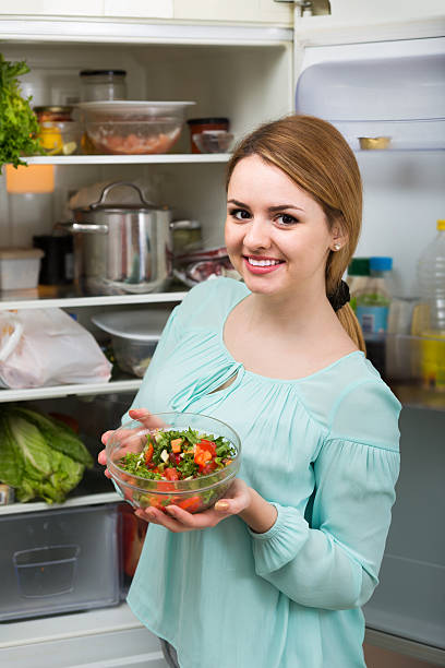 istock long-haired woman arranging space in fridge at home 515855452