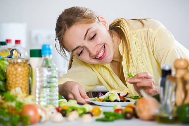 istock Cheerful girl decorating fresh salad with herbs 515858456