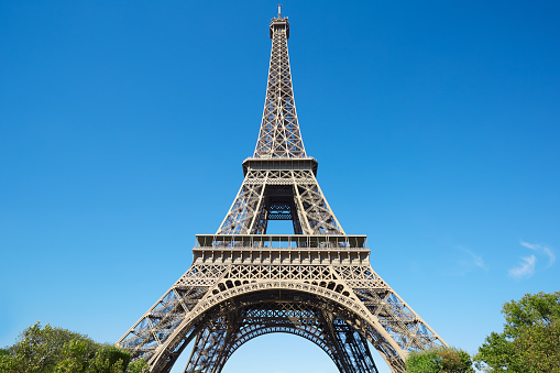 Eiffel tower, sunny summer day with clear blue sky and trees, summer in Paris, low angle view 