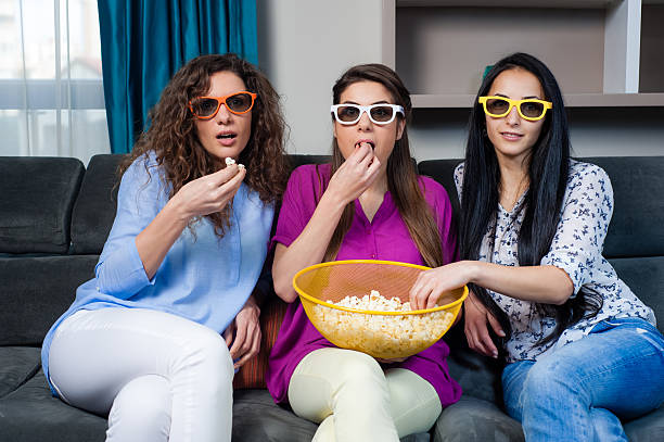 Movie and pizza time with girls Fun Movie with Girlfriends. Three smiling girls eating pizza while watching a movie at home. family eating potato chips stock pictures, royalty-free photos & images