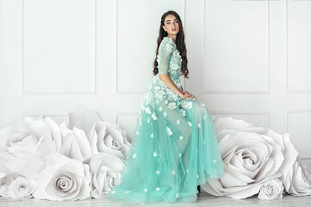 Studio shot of young beautiful woman on background of big flowers. Professional make-up and hairstyle.
