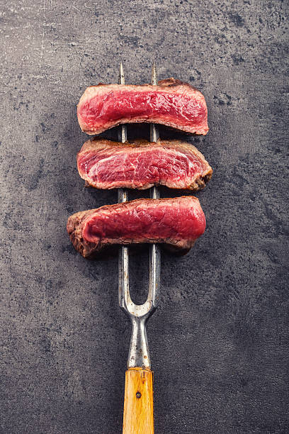istock Slices of sirloin beef steak on meat fork 515888002