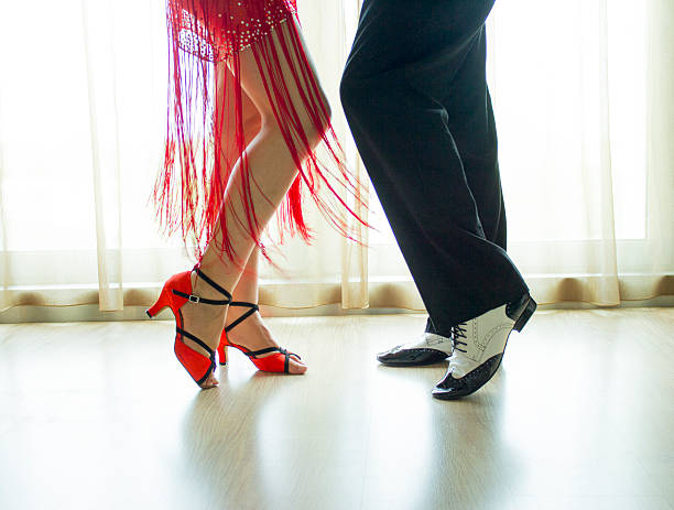 Male latin and salsa dancer in black and white jazz dancing shoes in light and dark on stage in nightclub dicoteque on dancefloor.