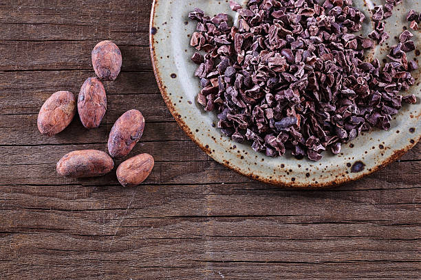 Raw Cacao Nibs and cacao beans over rustic wooden background stock photo