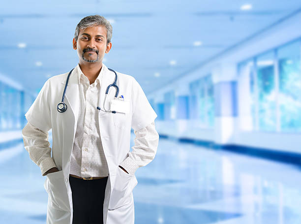 Indian doctor. Indian doctor. Mature Indian male medical doctor standing inside hospital. Handsome Indian model portrait. india hospital stock pictures, royalty-free photos & images