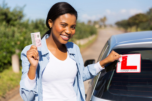 african woman removing learner driver sign after getting her driving license