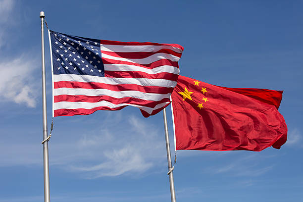 americano cinese giornata ventosa bandiere volare insieme sul pennone - chinese flag foto e immagini stock