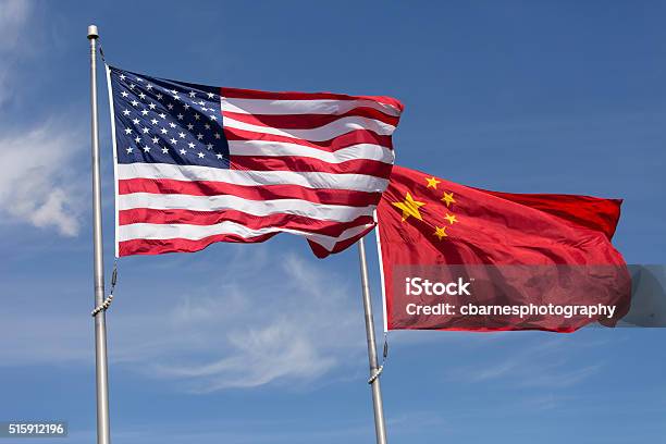 American Chinese Windy Day Flags Fly Together On Flagpole Stock Photo - Download Image Now