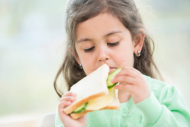 istock Cute girl eating sandwich at home 515912311