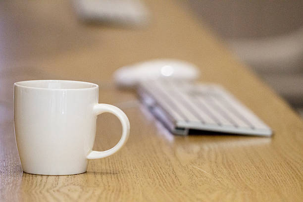 istock white porcelain cup and PC keyboard on office table 515913102
