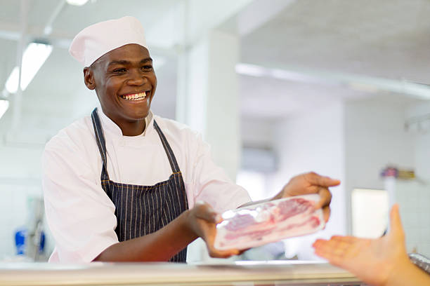 africano responsabile di macelleria/pescheria che vendono carne bovina al cliente - meat supermarket butchers shop market foto e immagini stock