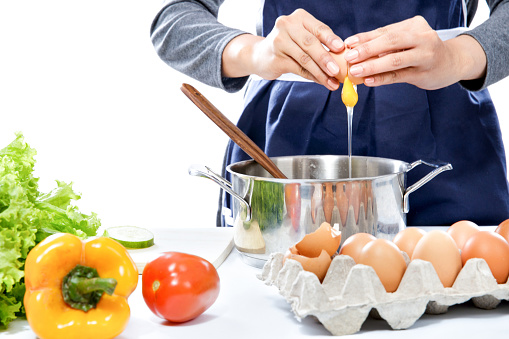 close up portrait of hands of housewife breaking an egg making a meal isolated on white