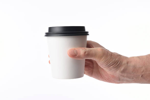 istock Holding a blank disposable paper coffee cup against white background 515921800