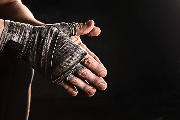 Close-up hand of muscular man with bandage Close-up hand with bandage of muscular man training kickboxing  on black  boxing gym stock pictures, royalty-free photos & images
