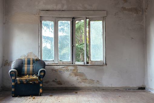 Room in an abandoned house with window and armchair