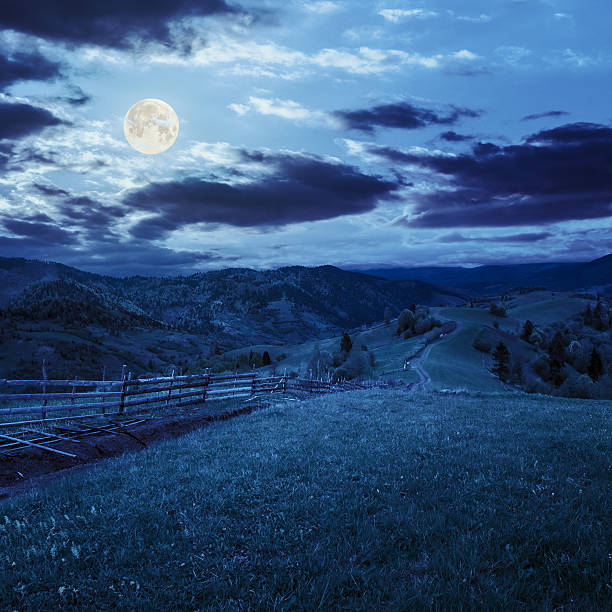 istock fence on hillside meadow in mountain at night 515928987