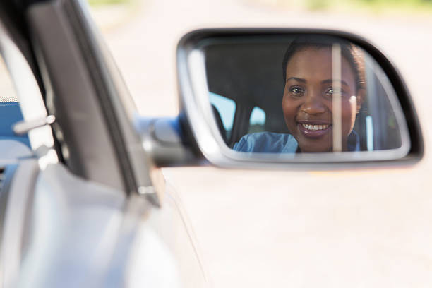 istock young african female driver looking at side mirror 515930001