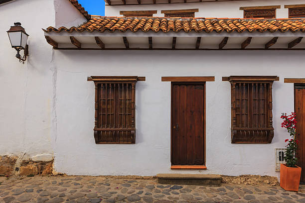 Villa de Leyva - Colombia, September 14, 2014: An old door and windows facing a street, in the 16th century town of Villa de Leyva in Colombia, South America.  It is an example of colonial Spanish architecture. Founded in 1572 and located at just over 7000 feet above sea level on the Andes Mountains, Villa de Leyva was declared a National Monument in 1954 to protect it's colonial architecture and heritage. It is located in the Department of Boyaca, in Colombia. Photo shot in the morning sunlight; horizontal format. No people. Copy space.