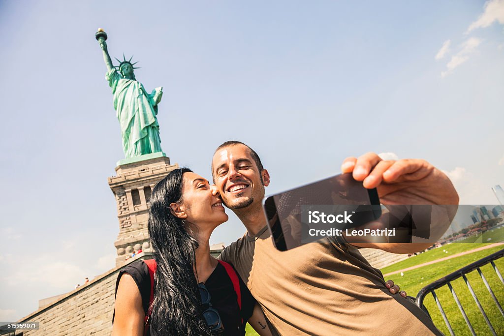 Taking a selfie in front of Statue of Liberty A couple taking a selfie in front of Statue of Liberty in Liberty Island. Statue of Liberty - New York City Stock Photo