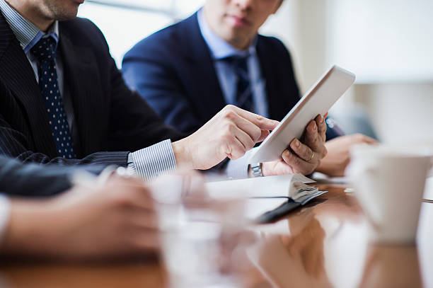 Three businessmen meeting in a conference room. Male boss is in progress a meeting while using a digital tablet in pride we trust stock pictures, royalty-free photos & images