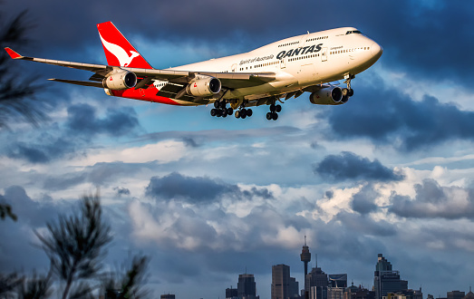 Sydney Australia March 15, 2016, Boeing 747-400 wearing Qantas Airlines colour scheme, arriving late afternoon at Kingsford Smith airport from Bangkok Thailand, with the city Skyline in the background