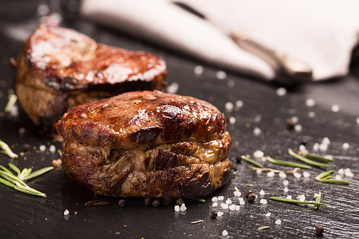 Grilled steak meat (mignon) on the dark surface. Dark background