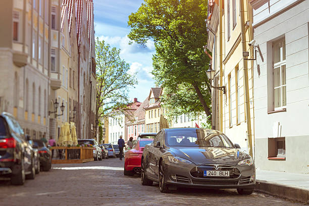 Tallinn, Estonia - June 12, 2015: Electric car, manufactured by Tesla motors, parked near the curb on a paved street of Tallinn, next there are historic buildings of old town. Estonia