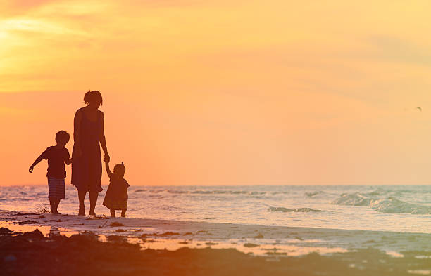 istock mother and two kids walking at sunset beach 516000252